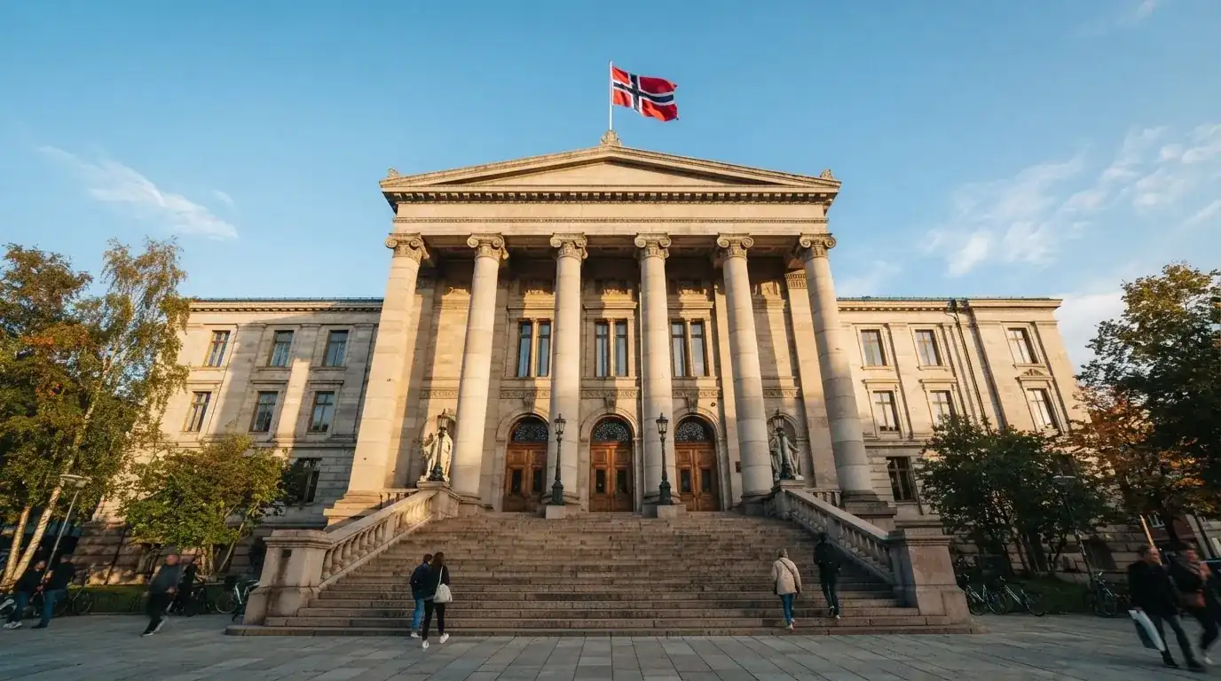Fasade av en stor offentlig bygning i Oslo med brede trapper og et norsk flagg i vinden under klar himmel